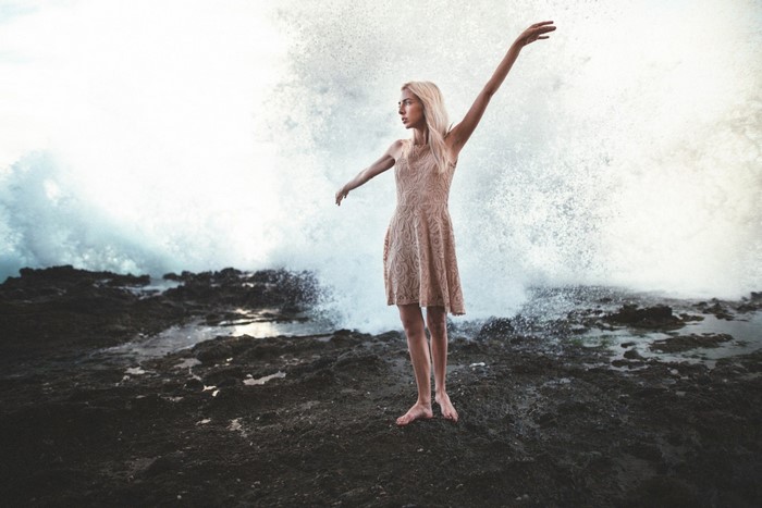 Woman in dress posing by ocean waves