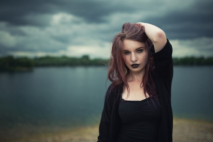 Woman with dark lipstick and nose ring by a lake