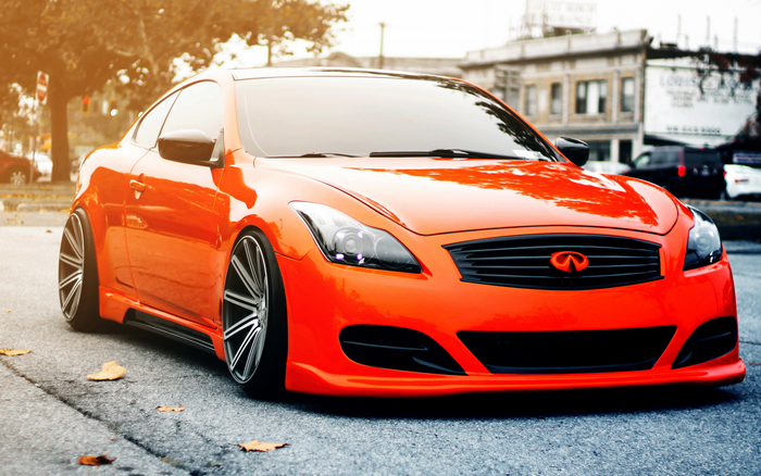 Orange Infiniti Q60 coupe with custom rims on street