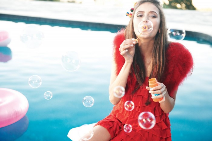 Nina Dobrev blowing bubbles by a swimming pool