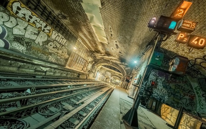 Graffiti-covered subway tunnel with train tracks and signal lights