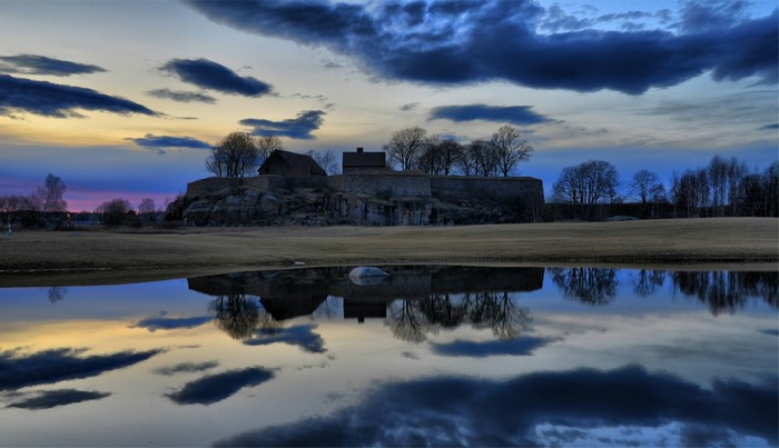 Castle ruins reflected in water at sunset