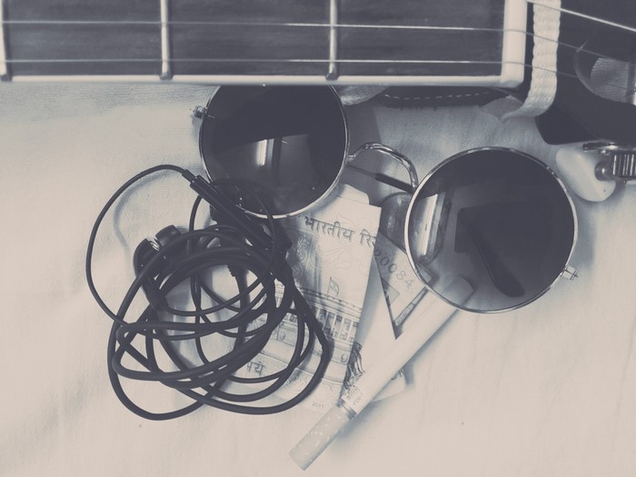Guitar, sunglasses, headphones, and Indian currency