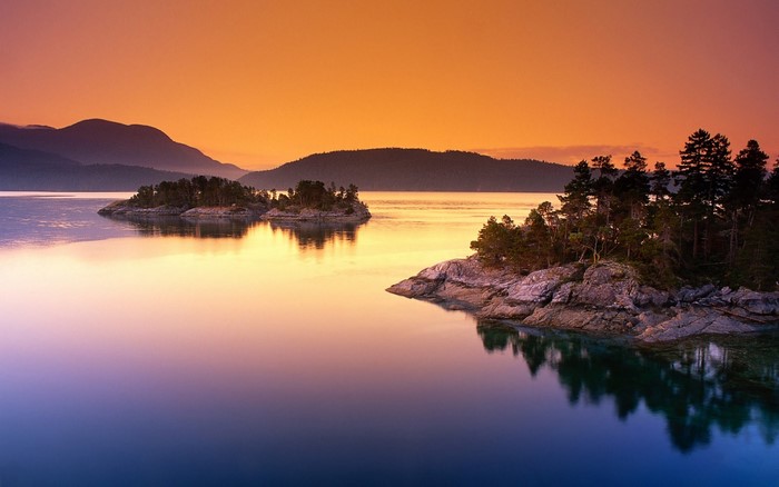 Islands and mountains at sunset over a calm lake
