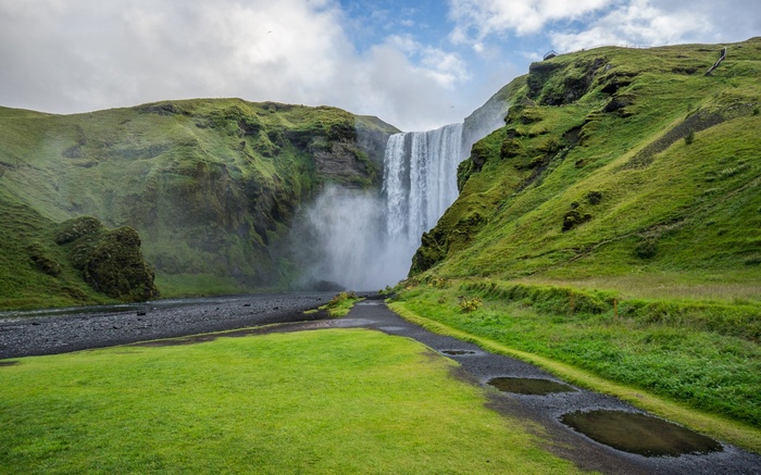 Skogafoss waterfall in Iceland with green hills