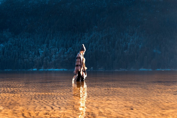 Woman in a poncho walking in a shallow lake