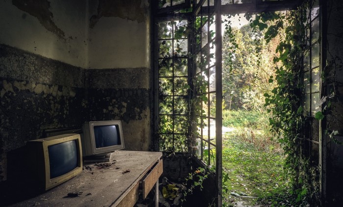 Abandoned room with old monitors and overgrown window