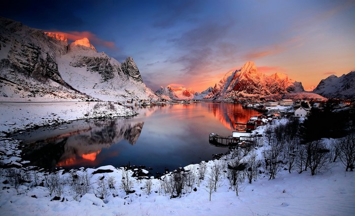 Snowy mountains reflecting in a lake at sunset in Norway