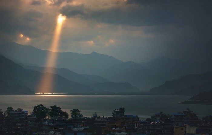 Sun rays over a lake and mountains in Nepal