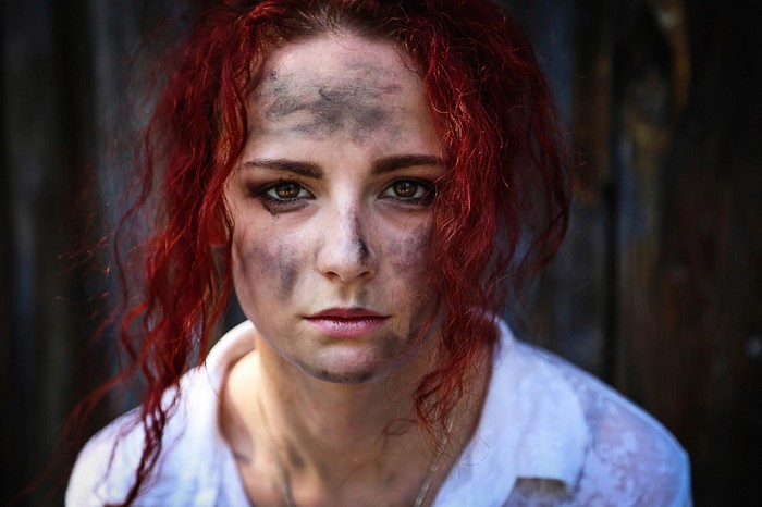 Woman with red hair and dirt on her face