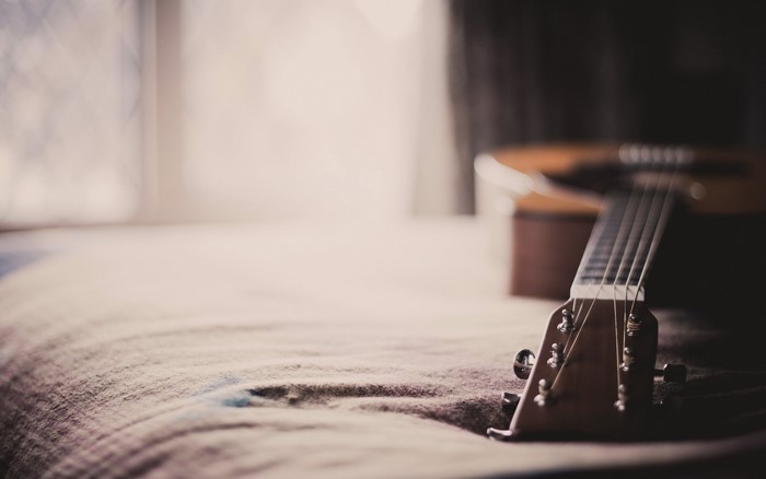 Acoustic guitar headstock on a bed