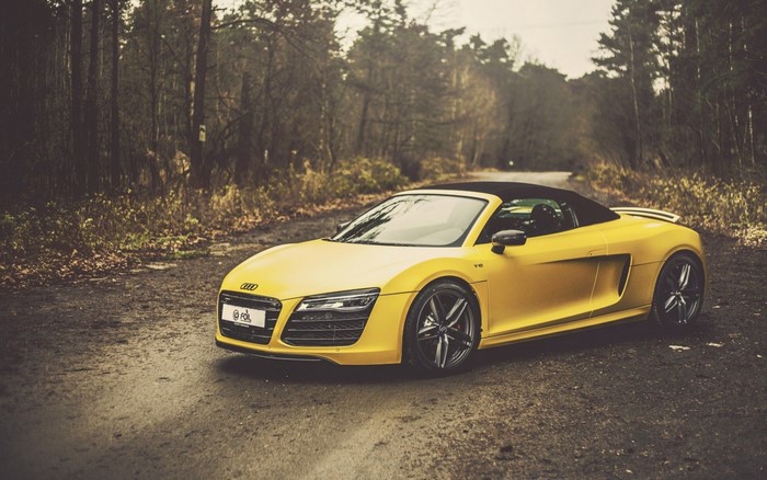 Yellow Audi R8 Spyder convertible sports car on a dirt road