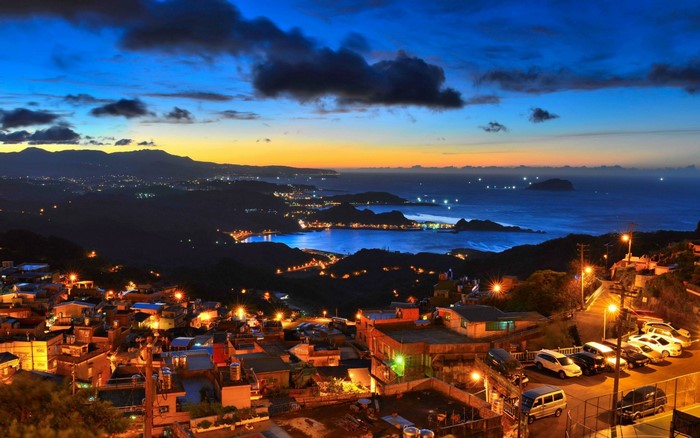 Coastal Cityscape at Dusk with Ocean and Mountains
