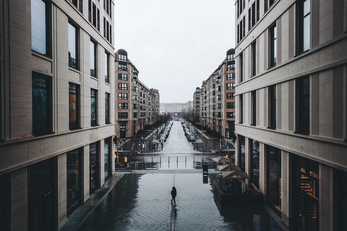 Person walking down a wet street between buildings in Berlin