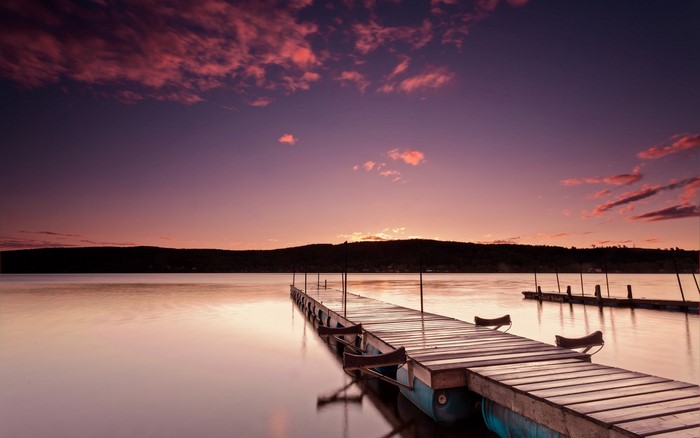 Wooden pier on a lake at sunset with colorful clouds