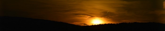 Sunset over a silhouetted mountain range with clouds