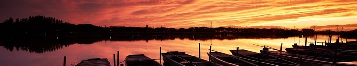 Panoramic sunset over a lake with boats
