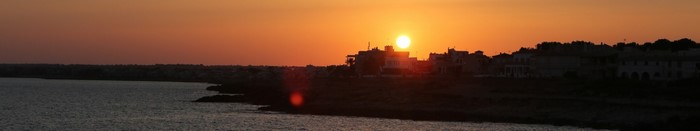 Sunset over a coastal town with the sea