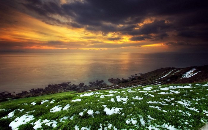 Sunset over the sea with snow-dusted hills