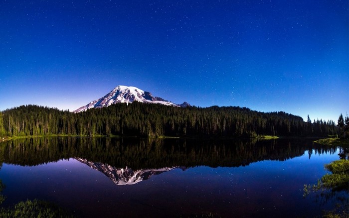 Mountain reflected in lake under starry night sky