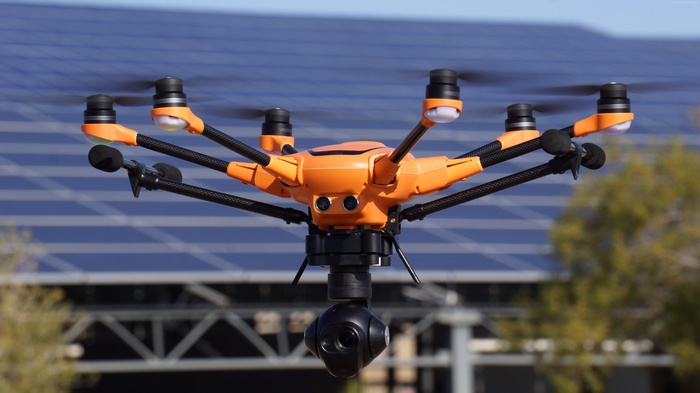 Orange Yuneec H520 drone flying near solar panels