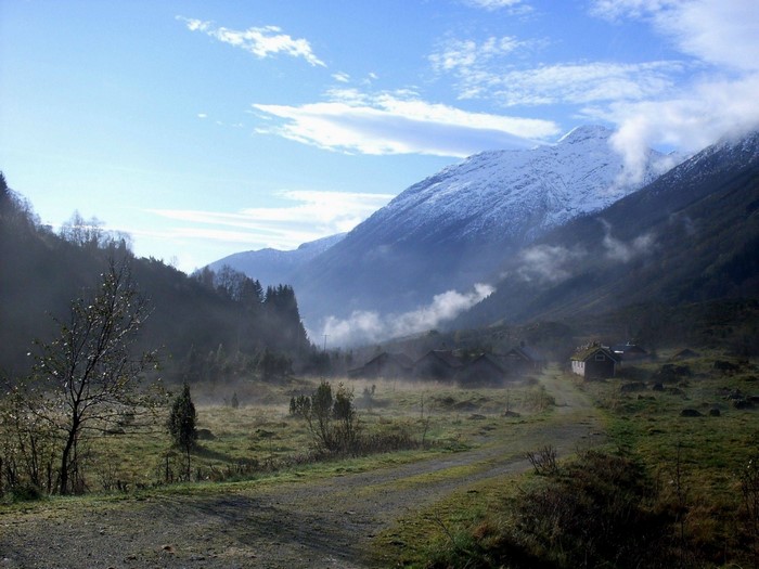 Misty valley with snow-capped mountains and a small village