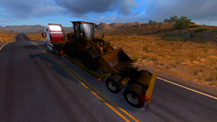 Volvo truck carrying a loader on a highway