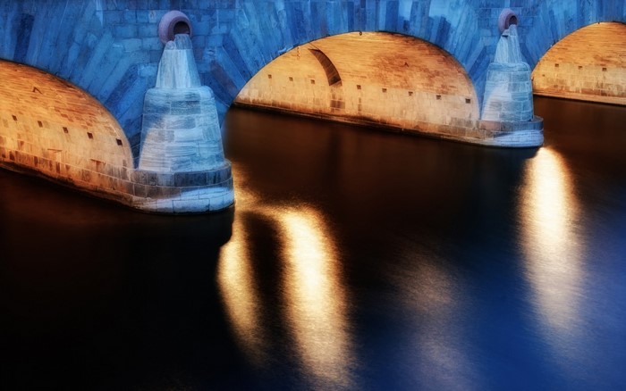 Bridge arches and reflections on water at night