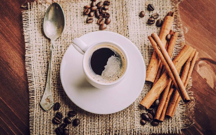 Coffee cup with cinnamon sticks and coffee beans