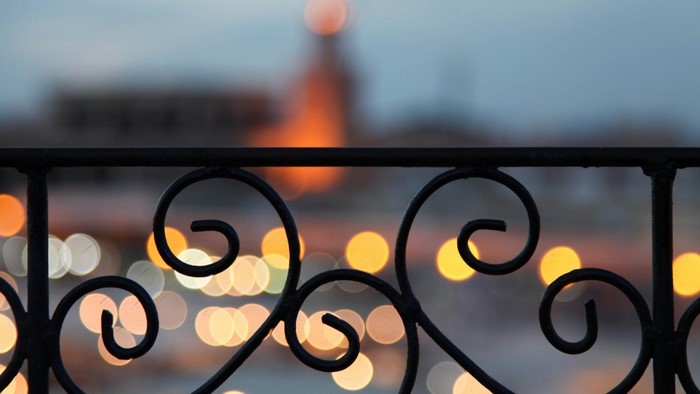 Ornate black railing with bokeh lights in the background
