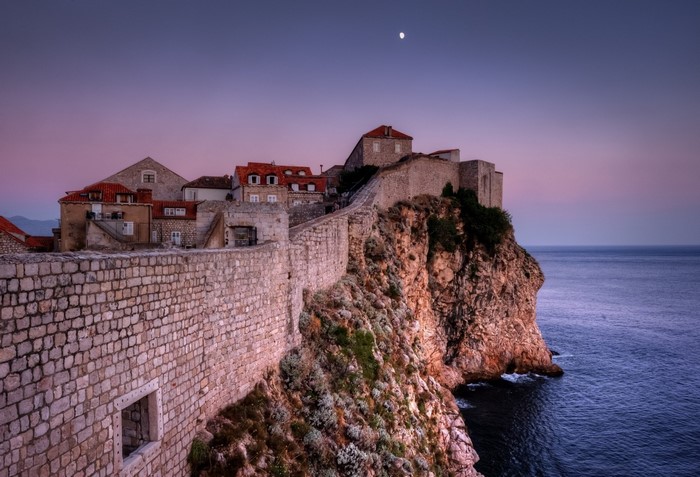 Dubrovnik old town walls on a cliff overlooking the sea at dusk