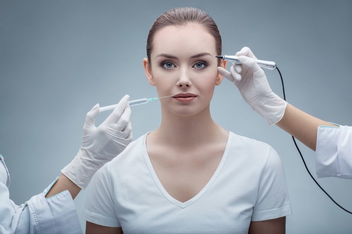 Woman receiving cosmetic injections and microblading