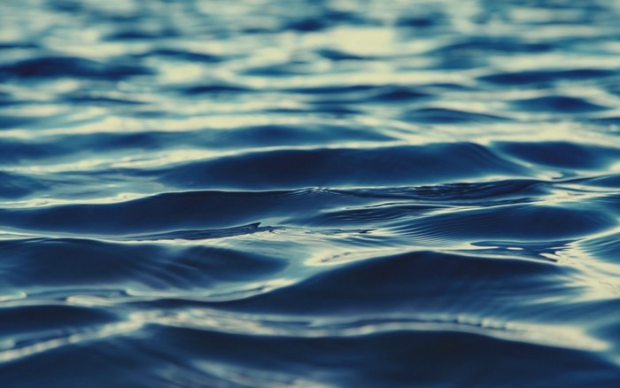 Close-up of blue ocean waves with sunlight reflection