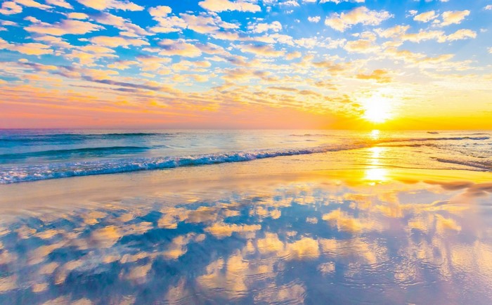 Sunset over the ocean with colorful clouds and reflection