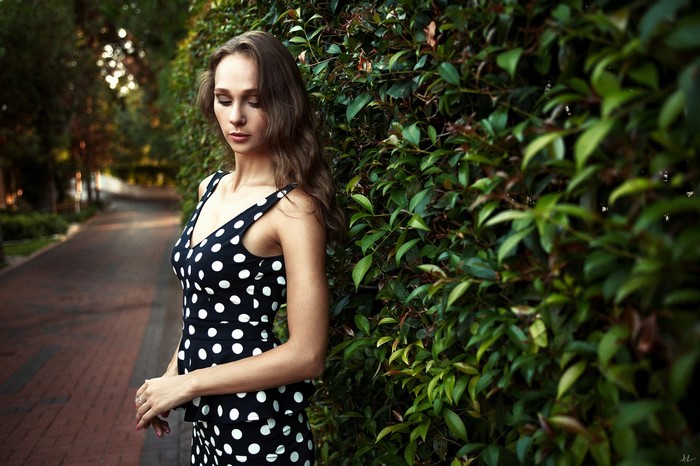 Woman in polka dot dress by a hedge