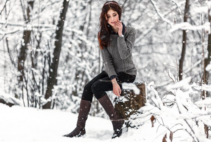 Woman in sweater and boots in snowy forest