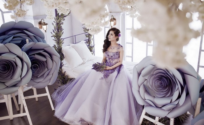 Woman in purple dress holding flowers in a decorated room