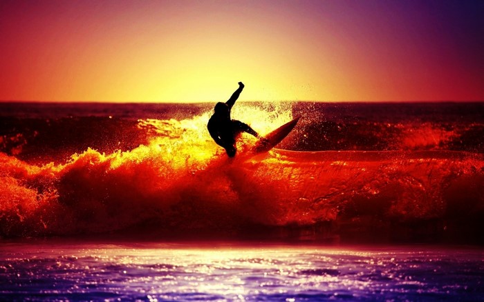 Surfer riding a wave at sunset