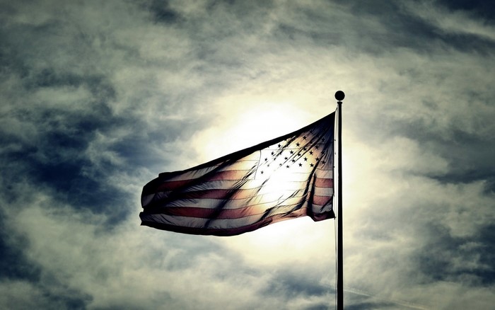 American flag waving in the sky with sunlight