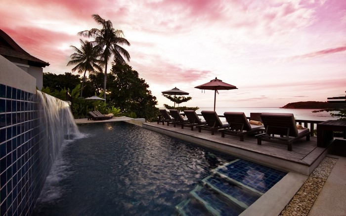 Tropical swimming pool at sunset with ocean view