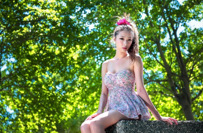 Young Woman in Floral Dress Sitting Outdoors