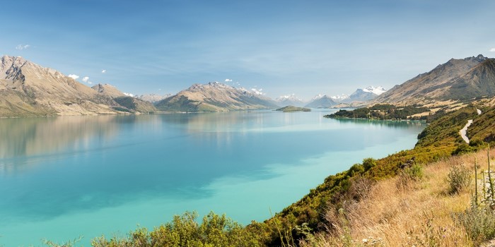 Turquoise lake reflecting mountains under a clear blue sky