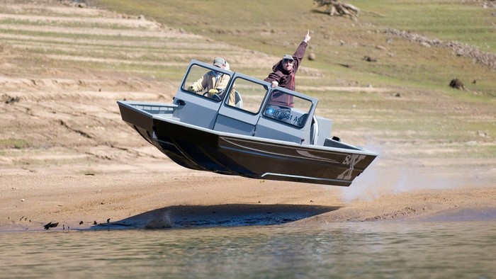 Boat jumping out of the water onto a sandy shore