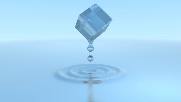 Ice cube melting into water with drops