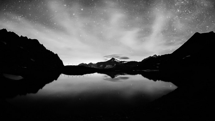 Mountain lake reflection under starry night sky
