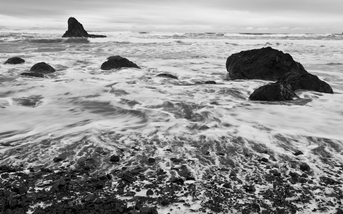 Monochrome image of waves crashing on rocks at the shore