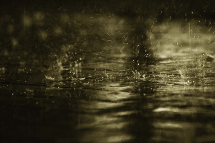 Raindrops hitting a dark, wet surface