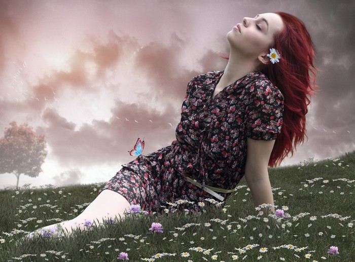 Woman with red hair and butterfly in a field of flowers