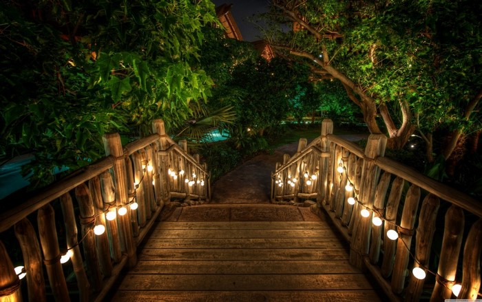 Wooden bridge with string lights at night
