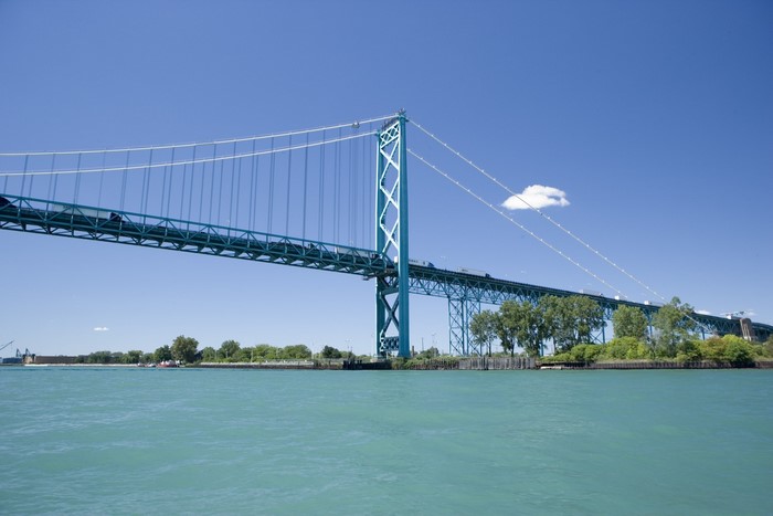 Suspension bridge over turquoise water under a clear blue sky